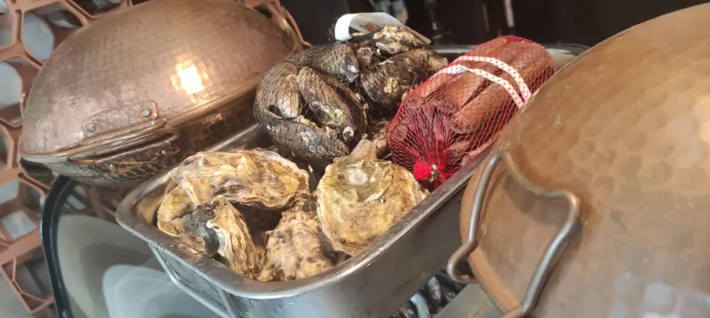 Ostras y marisco junto a las ollas de cobre